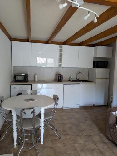 une cuisine avec des armoires blanches et une table et des chaises dans l'établissement Maison au bord de l'océan, à Vaux-sur-Mer