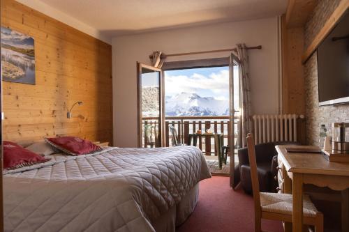 a bedroom with a bed and a window with a mountain view at Le Castillan in L'Alpe-d'Huez