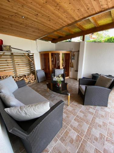 a patio with wicker furniture and a wooden ceiling at Haus Zimba Ferienwohnung am Bartholomäberg in Bartholomäberg