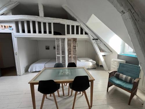 une chambre avec une table, des chaises et un lit superposé dans l'établissement Cabine du Capitaine 5, à Fécamp