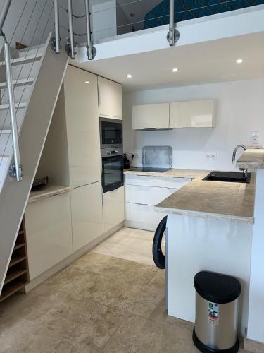 une cuisine avec des placards blancs et un escalier dans l'établissement Maison des Sables - A côté de la Plage dans le Golfe de Saint-Tropez, à Grimaud