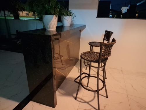 a black counter with a stool and a bar with plants at Casa completa para COP30 in Castanhal