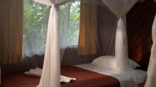 a bedroom with a canopy bed with white curtains at Shandia Lodge in Tena