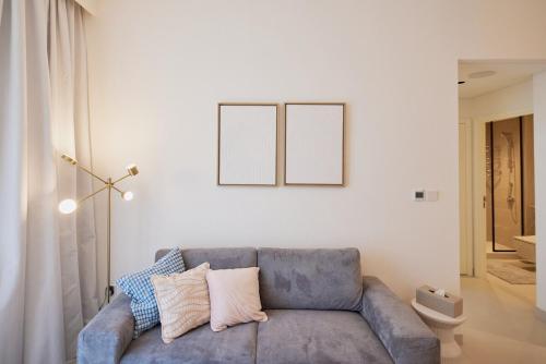 a living room with a blue couch and two frames on the wall at Stylish 1BR Warm & Curated Interiors in Dubai