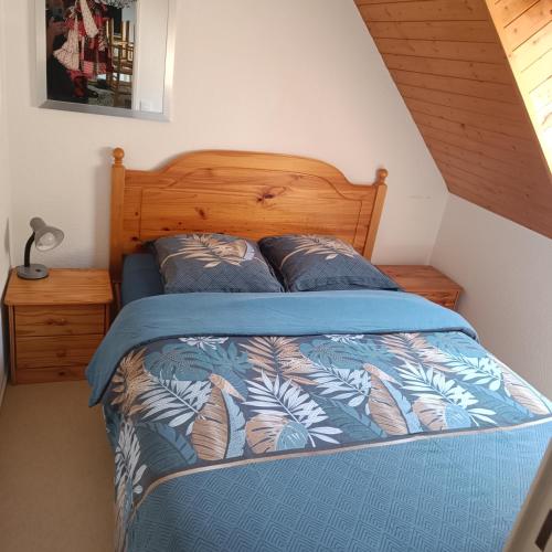 - un lit avec une couette bleue et 2 oreillers dans l'établissement Joli T2 avec alcôve Wifi 4 pers linge de maison inclus, à Cauterets