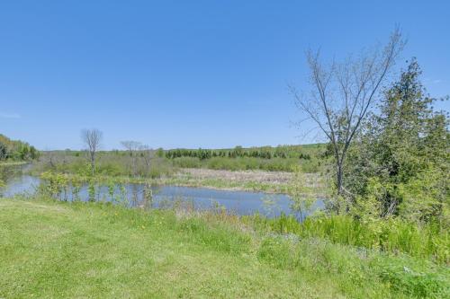 a river in the middle of a grassy field at Pond Views Spacious Family Home in Presque Isle! in Presque Isle