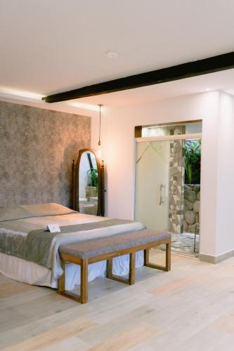 a bedroom with two beds and a bench at Tunas & Cabras Hotel in Ibarra