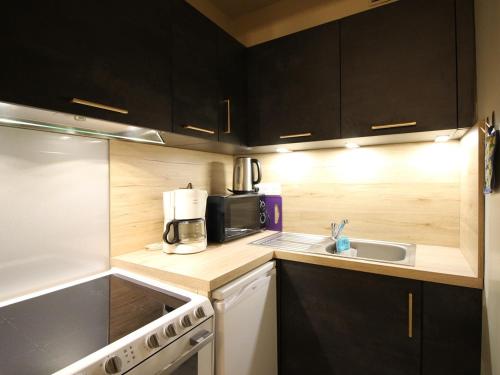- une petite cuisine avec des placards noirs et un évier dans l'établissement Appartement T2 avec balcon, parking et WIFI au Mont-Dore - FR-1-608-141, à Le Mont-Dore