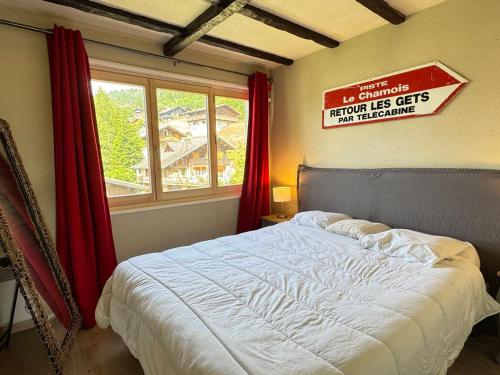 une chambre avec un lit avec un panneau sur le mur dans l'établissement Appartement cosy avec balcon, wifi et garage aux Gets - FR-1-623-159, aux Gets