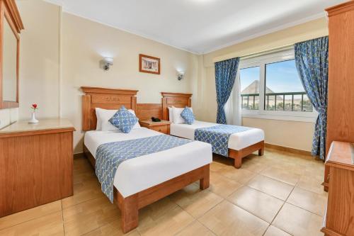 una camera d'albergo con due letti e una finestra di Aura Inn Tiba Pyramids Hotel a Giza