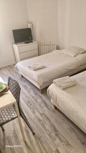 une chambre avec deux lits, une table et une chaise dans l'établissement Suite Cosy Gare&TNB à 200 m - 3 personnes - Rennes, à Rennes
