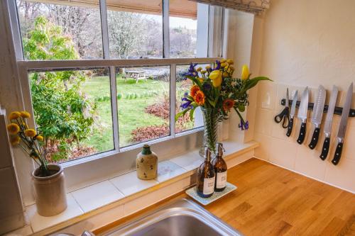 a kitchen window with a vase of flowers on a counter at Castle Cottage No 2 in Acharn