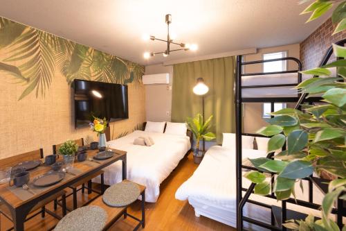 a room with two beds and a table and chairs at LEON RESORT HOTEL Makuhari & Tsudanuma Disney & Narita Airport Narashino by LEON RESORT 幕張 津田沼 習志野 in Narashino
