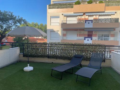 - deux chaises et un parasol sur le balcon dans l'établissement Arcachon centre, à Arcachon