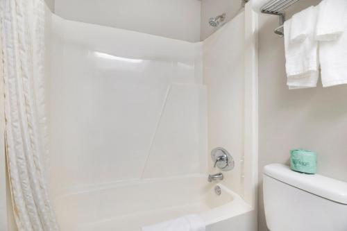a white bathroom with a shower and a toilet at Days Inn & Suites by Wyndham Norton Shores Muskegon in Norton Shores