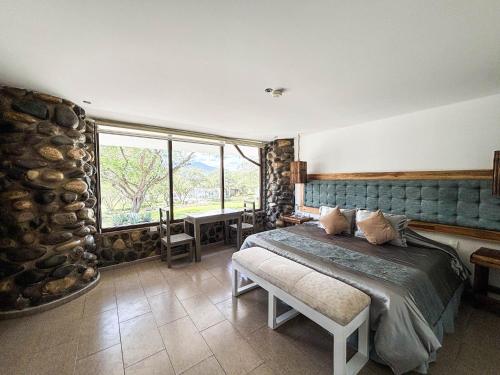 a bedroom with a bed and a large window at Tunas & Cabras Hotel in Ibarra