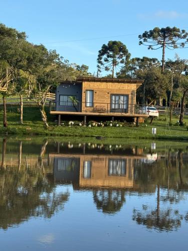 a house with a reflection in the water at Cabana Lago Campestre in Urubici