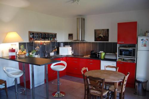 une cuisine avec des armoires rouges et une table et des chaises dans l'établissement Ines - Maison climatisée pour 4 pers a 5min d'Avignon, à Villeneuve-lès-Avignon