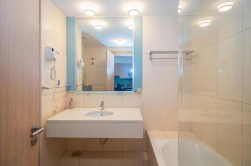 un bagno con un lavandino, una vasca e uno specchio di KÁ RICARDO - STUDIO 206 Vila Verde a Santa Maria