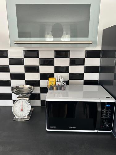 a microwave sitting on a counter next to a clock at Domaine Baccia Donna Proche Nice, Climatisation, Jacuzzi chauffé, Pétanque & Parking gratuit in La Trinité