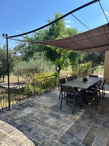 a patio with a table and chairs and an umbrella at L'ostal de la Patz in Saint-Julien-de-la-Nef