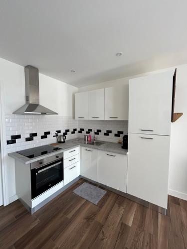 a white kitchen with white appliances and wooden floors at Domaine Baccia Donna Proche Nice, Climatisation, Jacuzzi chauffé, Pétanque & Parking gratuit in La Trinité