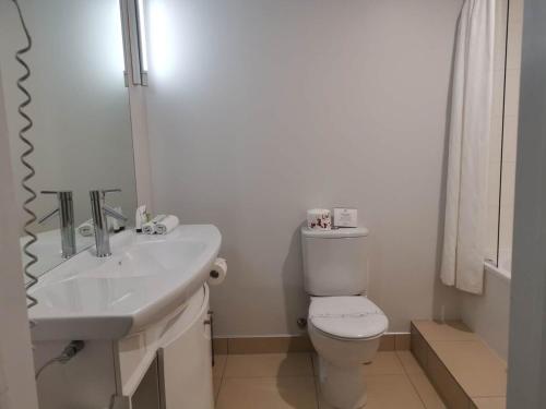 a white bathroom with a toilet and a sink at Littoral Living in Tauranga