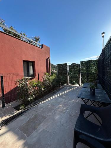 a patio with a table and a fence and a building at Domaine Baccia Donna Proche Nice, Climatisation, Jacuzzi chauffé, Pétanque & Parking gratuit in La Trinité