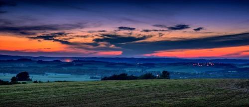 a field with a sunset in the background with a sky at Karavan na samotě u lesa 