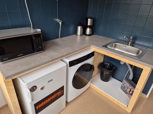 a kitchen with a sink and a washing machine at NATO bunker with nice bed and appliancies in Mikkeli