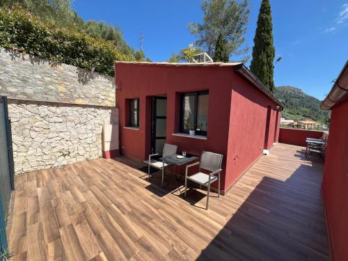 a red house with a wooden deck with a table and chairs at Domaine Baccia Donna Proche Nice, Climatisation, Jacuzzi chauffé, Pétanque & Parking gratuit in La Trinité
