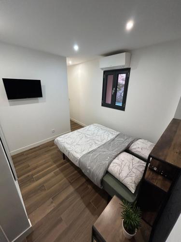 a bedroom with a bed and a tv on the wall at Domaine Baccia Donna Proche Nice, Climatisation, Jacuzzi chauffé, Pétanque & Parking gratuit in La Trinité