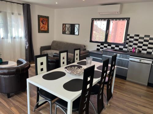 a kitchen and living room with a white table and chairs at Domaine Baccia Donna Proche Nice, Climatisation, Jacuzzi chauffé, Pétanque & Parking gratuit in La Trinité