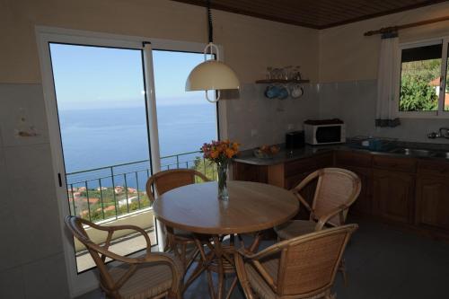 eine Küche mit einem Tisch und Stühlen sowie einen Balkon in der Unterkunft Casa Daniela in Calheta