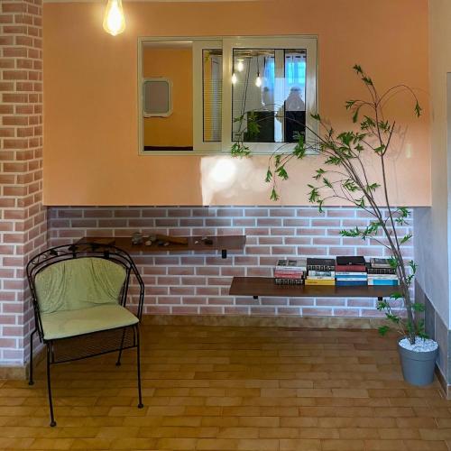 a chair in front of a brick wall with a mirror at Paola's Garden in Carbonia