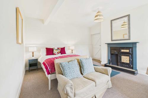 ein Schlafzimmer mit einem Bett und einer Couch und einem Kamin in der Unterkunft Host & Stay - Bell Cottage in Kirknewton