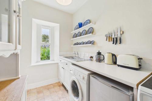eine Küche mit Waschmaschine und Fenster in der Unterkunft Host & Stay - Bell Cottage in Kirknewton