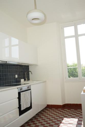 - une cuisine avec des placards blancs et un sol en damier dans l'établissement Flat la Croisette Cannes La Croix d'Or 3, à Cannes