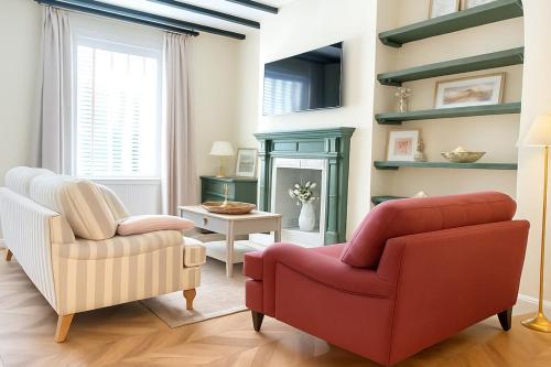 a living room with two chairs and a red chair at Renas Seahaven Cottage in Cullercoats