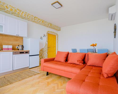 a living room with an orange couch and a kitchen at Villa Azur - Experience the Adriatic in Novi Vinodolski