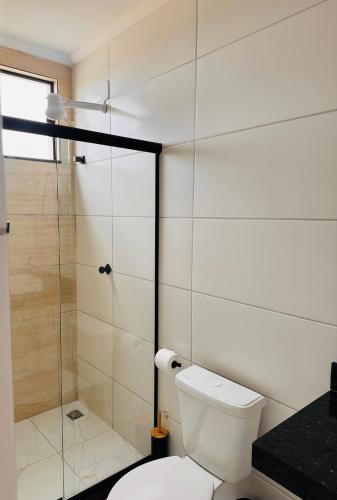 a bathroom with a toilet and a glass shower at Suítes da Orla Hospedagens in Arraial do Cabo