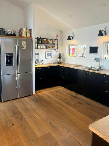 a kitchen with a stainless steel refrigerator and wooden floors at Architect-Designed House With Private Beach in Løgstrup