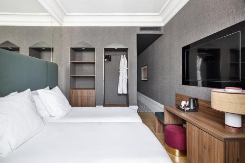 a hotel room with two beds and a television at One Shot Recoletos in Madrid