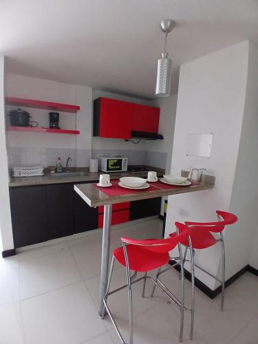 a kitchen with red cabinets and a table with red chairs at Hotel Plaza Norte Cali in Cali