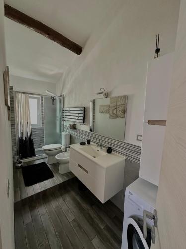 a white bathroom with a sink and a toilet at Ca' del Grillo in La Spezia