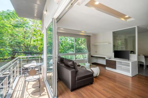 a living room with a black couch and a television at Story At Bangkok- 211 Studio with Balcony in Klong Toi
