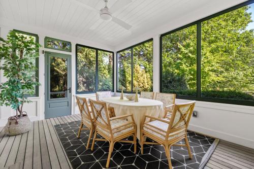 a dining room with a table and chairs and windows at Lavish Boston Mansion Pool, Gardens, Games, Pond! in Dedham