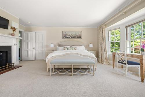 a white bedroom with a bed and a fireplace at Lavish Boston Mansion Pool, Gardens, Games, Pond! in Dedham