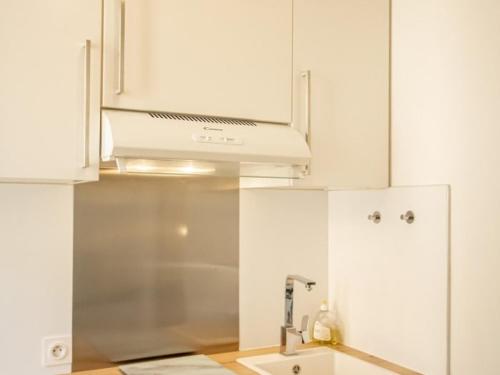a kitchen with white cabinets and a white stove top oven at Le studio 1900 - Centre-ville in Albertville