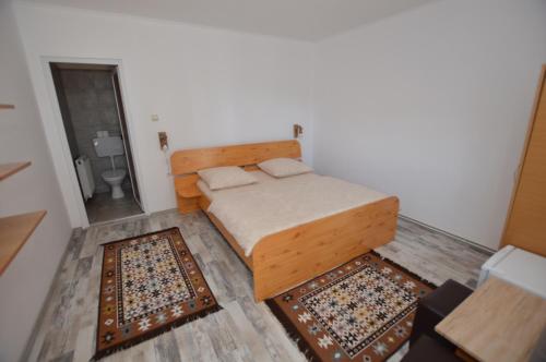 a small bedroom with a bed and two rugs at Cris & Mona in Săpînţa